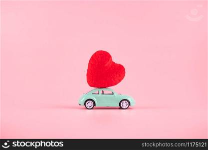 Red heart shape decoration on mini car toy with copy space for text on pink background. Love, Wedding, Romantic and Happy Valentine day holiday concept