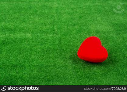 Red heart shape icon on fake green grass