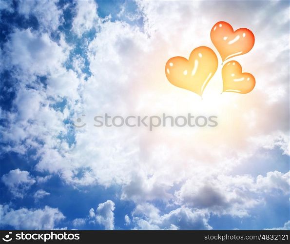 Red heart shaped inflatable balloons in blue cloudy sky, abstract romantic background, honeymoon, love concept