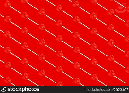 Red heart shaped lollipops placed together diagonally on a red background.. Red heart shaped lollipops placed together diagonally on a red background