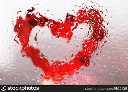 red heart under glass with water drops. abstract background with drops of water and painted heart on the surface. Valentines background, love, date concept. Red heart under glass surface with water drops close. Valentines background, love, date concept