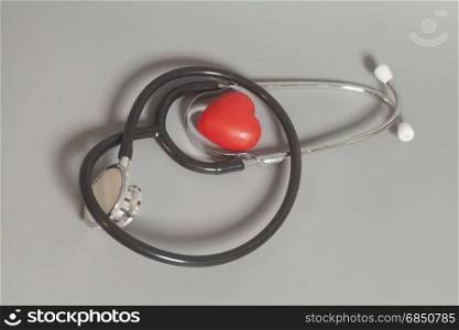 Red heart with a medical stethoscope on gray background