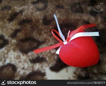 Red heart with red and white stripes on the brown background