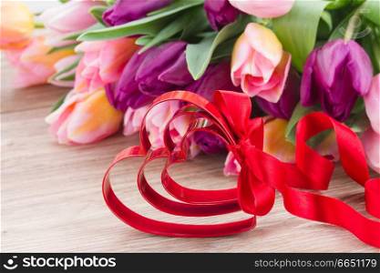 red hearts and bow with pink and purple tulips in background