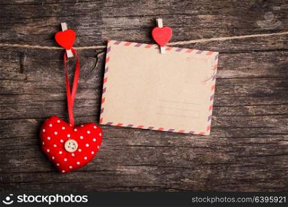Red hearts and paper card hanging on the rope by red clips on rustic background. The concept of Valentine&rsquo;s Day