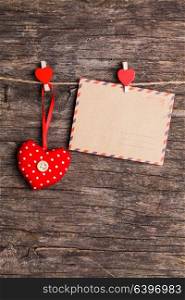 Red hearts and paper card hanging on the rope by red clips on rustic background. The concept of Valentine&rsquo;s Day