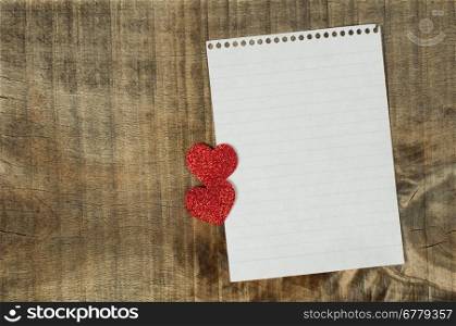 Red hearts and white paper sheet on wooden background