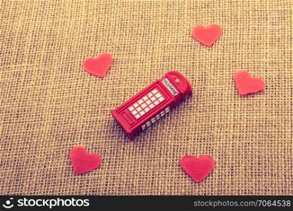 Red hearts around red color phone booth on canvas
