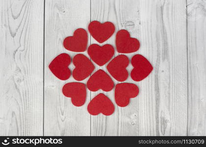 red hearts forming a geometric figure in the centre of a white and grey wooden background. concept of valentine's day