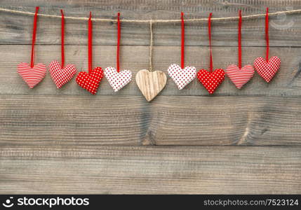 Red hearts hanging on clothesline over wooden background. Valentines Day