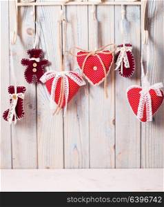 Red hearts hanging on the hooks. Christmas greetings. Hearts on hooks