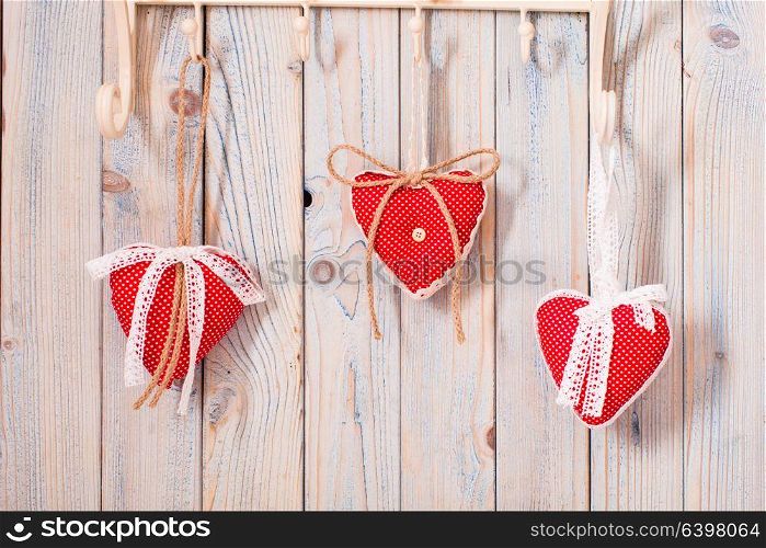 Red hearts hanging on the hooks.Christmas or Valentine greetings. Hearts on hooks