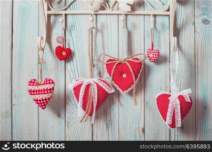 Red hearts hanging on the hooks.Christmas or Valentine greetings. Red hearts hanging