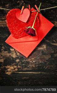 Red hearts, rose and envelop hanging on the clothesline. On old wood background
