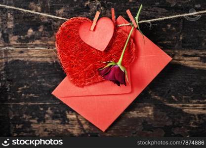 Red hearts, rose and envelop hanging on the clothesline. On old wood background