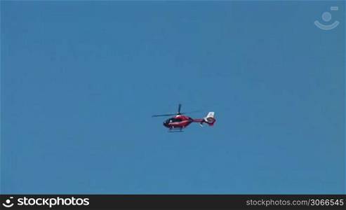 red helicopter flying in the blue sky