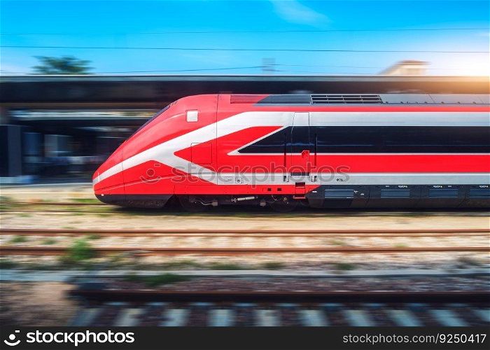 Red high speed train in motion on the railway station. Fast moving modern intercity train and blurred background. Railway platform. Railroad in Italy. Commercial and passenger railway transportation 