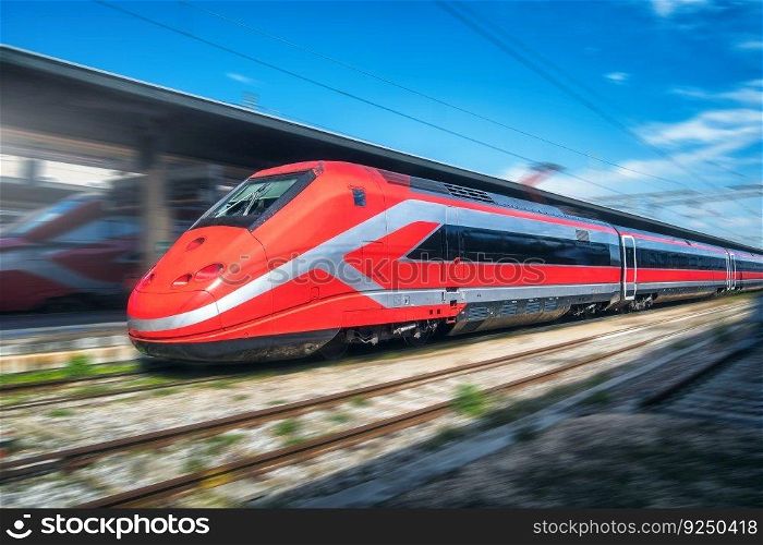 Red high speed train in motion on the railway station. Fast moving modern intercity train and blurred background. Railway platform. Railroad in Italy. Commercial and passenger railway transportation	