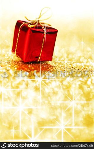 Red holiday gift box on shiny golden background with copy space