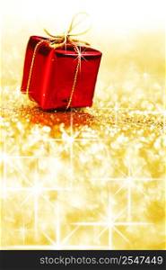 Red holiday gift box on shiny golden background with copy space