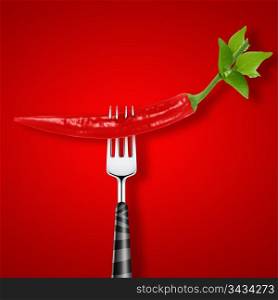 red hot chili pepper pierced by fork on red background .. red hot chili pepper