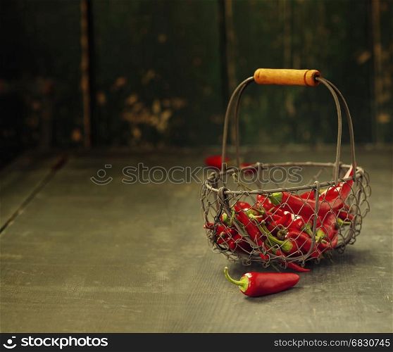 Red hot chili peppers in a metal basket on a wooden background