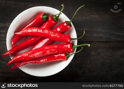 Red hot chili peppers on white plate on table background. Copy space. Top view