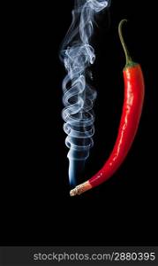 Red hot chilli pepper with smoke coming out of tip which is burning and glowing