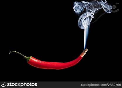 Red hot chilli pepper with smoke coming out of tip which is burning and glowing