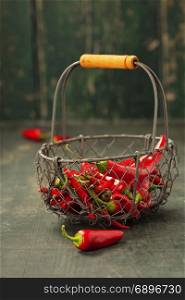 Red hot chilli peppers in a metal basket on a wooden background