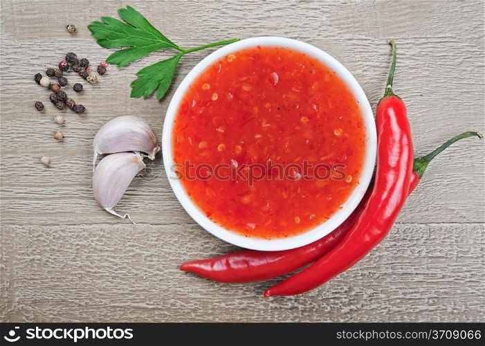red hot chilli sauce over wooden background