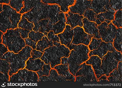 Red hot lava through the cracked ground background. Magma texture and the black burned ground. Active volcano surface.