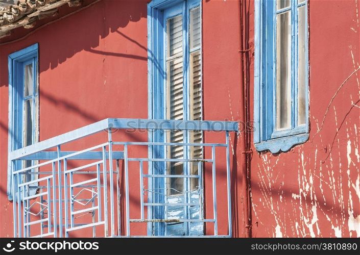 Red house facade with blue balcony door and windows