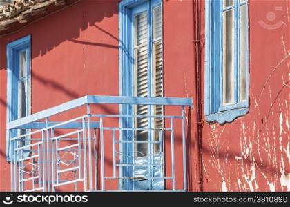 Red house facade with blue balcony door and windows