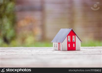 Red house model on the floor, outdoors. Concept for new home, property and estate, copy space