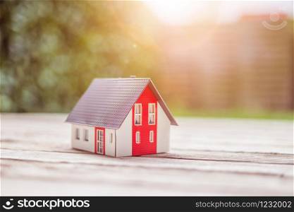 Red house model on the floor, outdoors. Concept for new home, property and estate