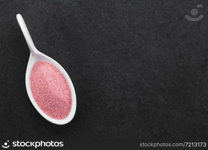 Red instant jelly or jello powder on small spoon, photographed overhead on slate with copy space on the right side (Selective Focus, Focus on the powder). Red Jelly or Jello Powder