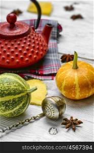 Red iron kettle,falling leaves and pumpkins on bright background