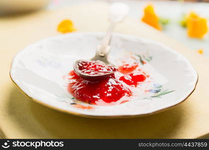 Red jam in plate with spoon, close up