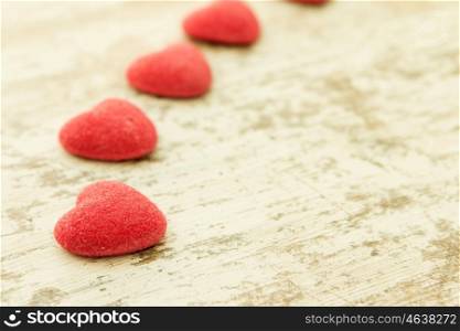 Red jelly beans hearts on a wooden background. Focus in the foreground