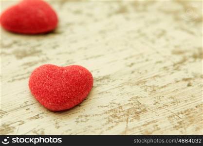 Red jelly beans hearts on a wooden background. Focus in the foreground