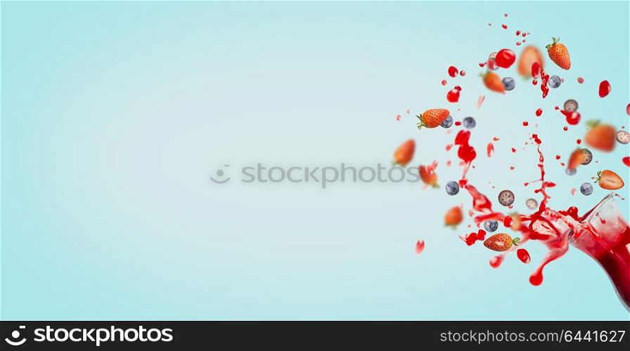 Red juice or smoothie drink is poured out of glass bottle with splash and berries ingredients on turquoise background, banner or template, front view. Healthy summer beverage concept