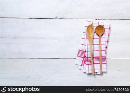 Red kitchen towel with cooking spoons on light wood background.. Red kitchen towel with cooking spoons on light wood background