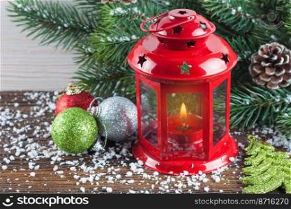 Red lantern with a burning candle and New Year decoration over snow and white wooden background with Christmas tree. Vintage filter effect. Lantern and Christmas tree over snow on wooden background
