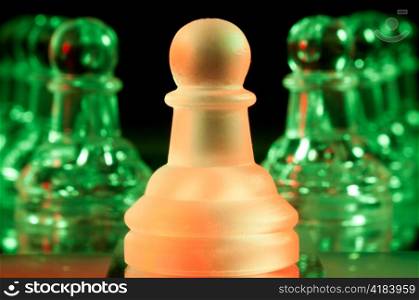 red leader and rows of green glass chess pawns is standing on board in dark