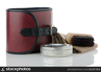 Red leather bad and container of shoe polish and brush on white background.