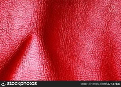 Red leather texture background closeup. Folds wavy natural skin material