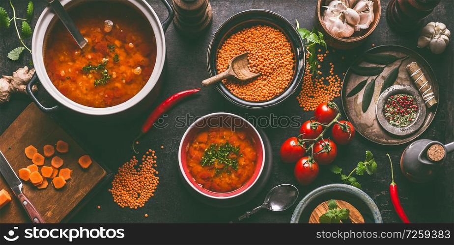 Red lentil soup with cooking ingredients on dark rustic kitchen table background, top view. Healthy vegan food concept. Vegetarian lentil meal dishes. Clean eating.
