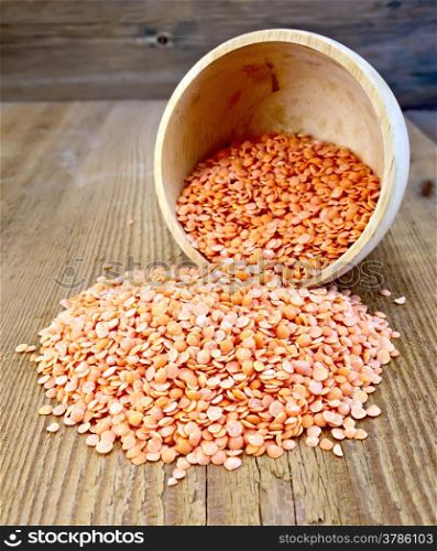 Red lentils in a wooden bowl on a wooden boards background