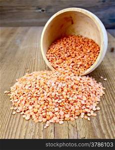 Red lentils in a wooden bowl on a wooden boards background